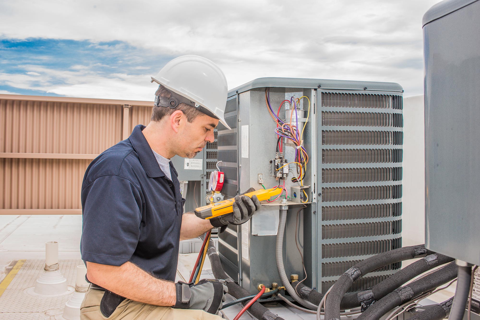 Technician fixing a Condenser Unit on a commercial building roof.