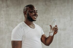 man in white t-shirt drinks bottle of water