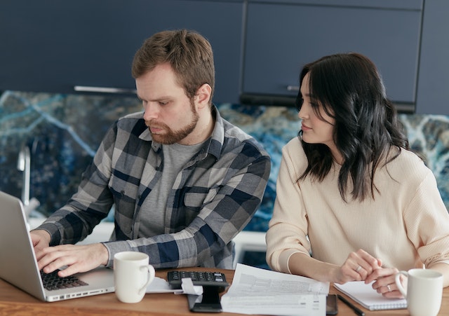 man and woman look at home budget on laptop