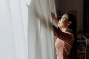 woman opens window curtains