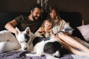 family with dog snuggles in comfortable bed