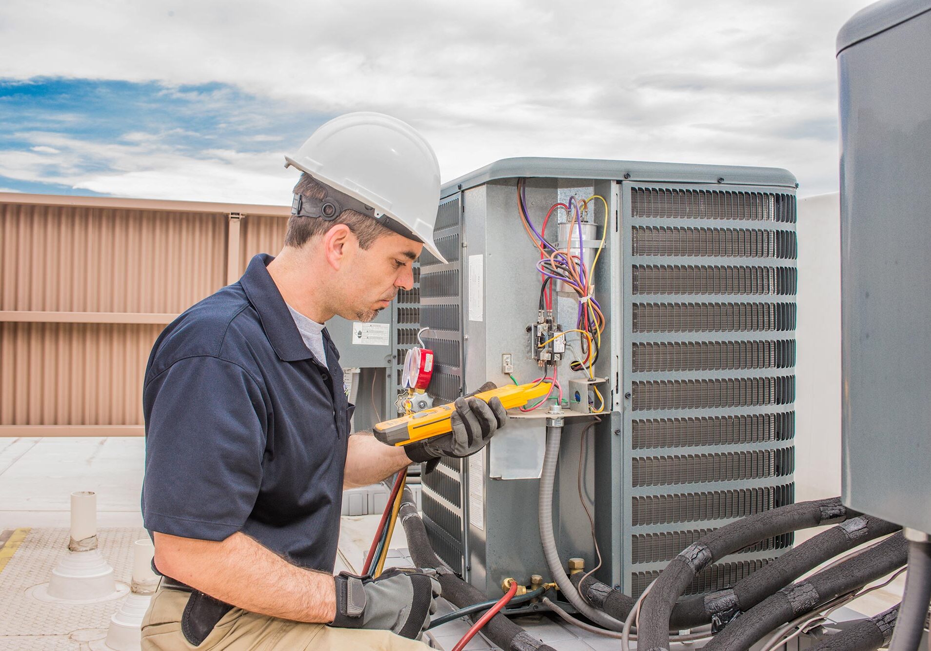 Technician fixing a Condenser Unit on a commercial building roof.