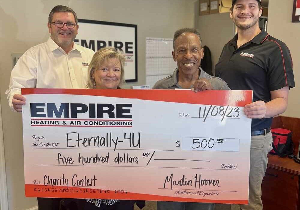 Empire Staff holding a large check to charity representative.