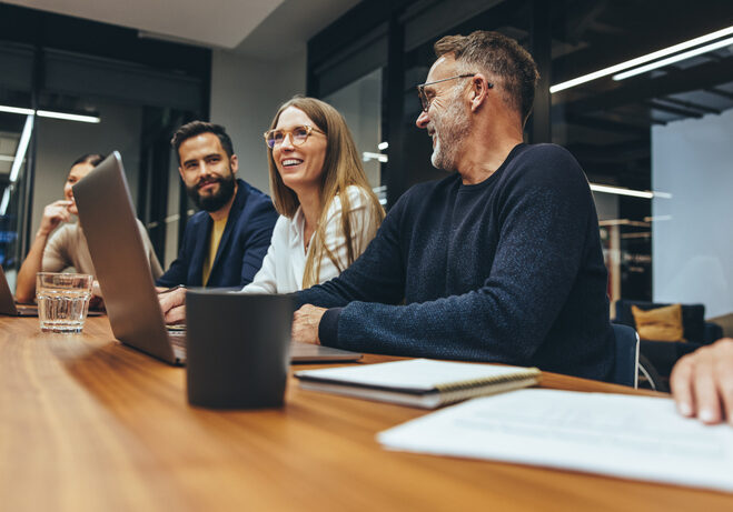 Successful group of businesspeople having a briefing in a boardroom. Happy businesspeople smiling while working together in a modern workplace. Diverse business colleagues collaborating on a project.