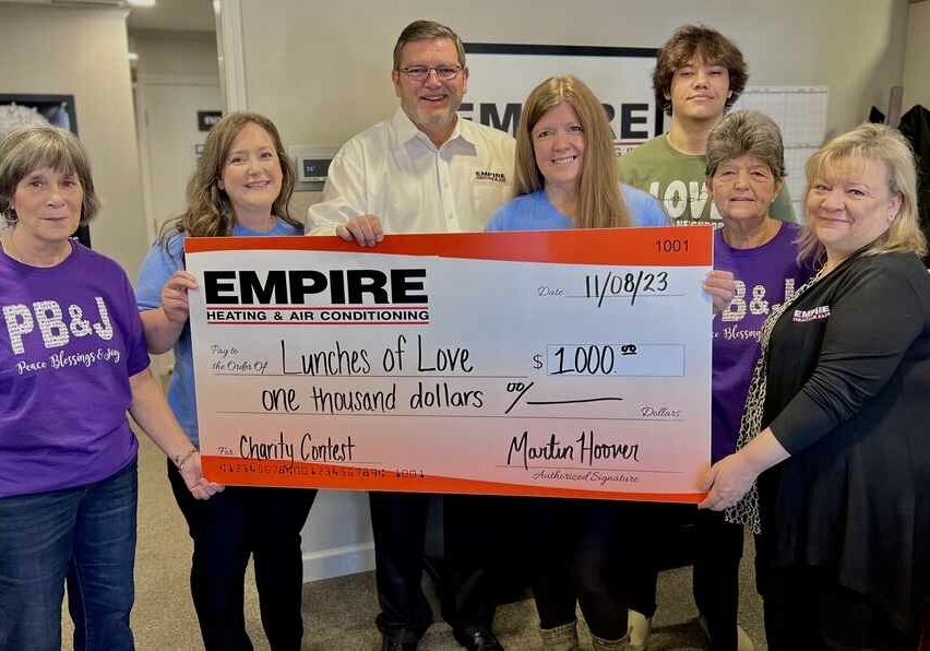 Empire staff holding check for Lunches of Love donation